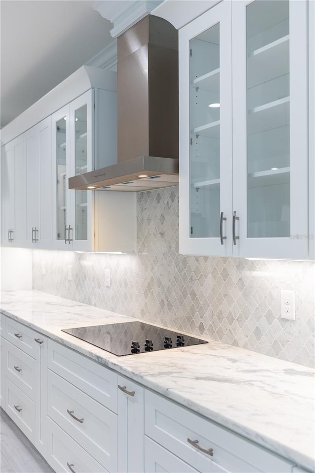 kitchen featuring wall chimney range hood, white cabinets, and tasteful backsplash