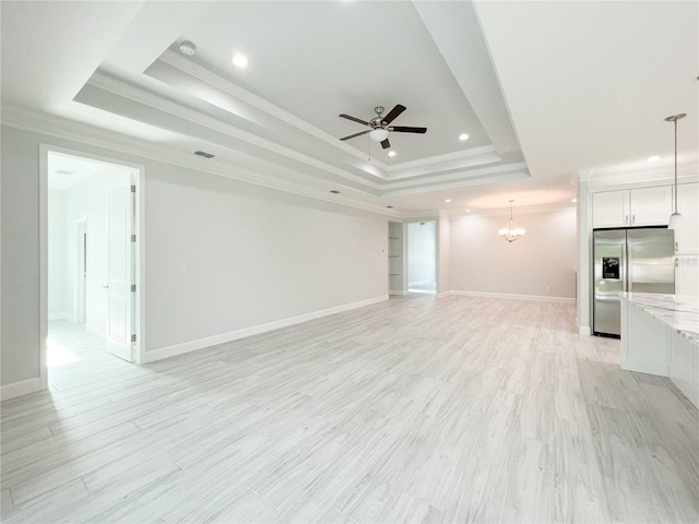 unfurnished living room featuring ceiling fan with notable chandelier, ornamental molding, a raised ceiling, and light hardwood / wood-style flooring