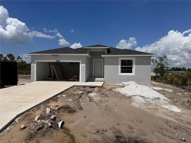 view of front facade with a garage, driveway, and stucco siding