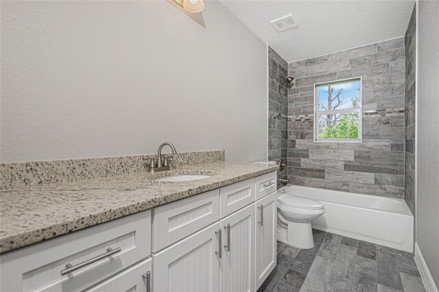 full bathroom with a textured ceiling, vanity, tile patterned flooring, toilet, and tiled shower / bath