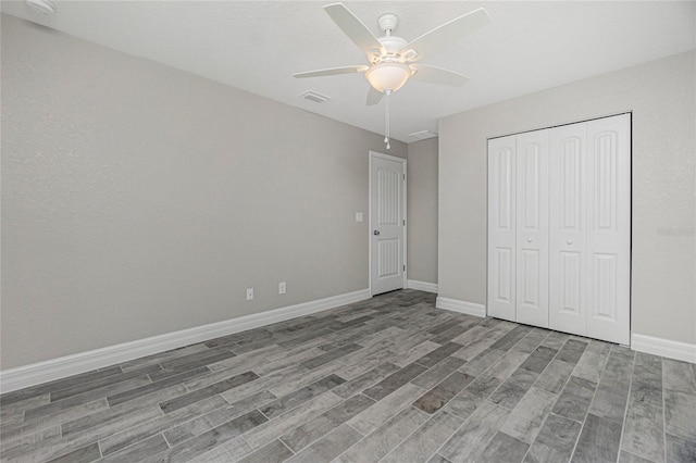 unfurnished bedroom with a closet, baseboards, wood finished floors, and a ceiling fan