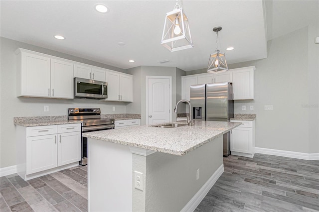 kitchen with a sink, white cabinets, appliances with stainless steel finishes, pendant lighting, and light wood-type flooring