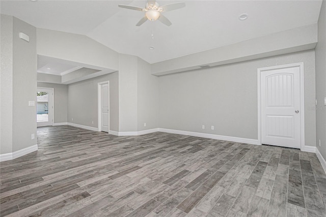 empty room with baseboards, wood finished floors, a ceiling fan, and vaulted ceiling