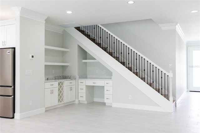 stairs with built in shelves, wood-type flooring, and ornamental molding