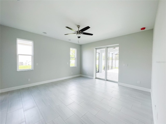 empty room with plenty of natural light, ceiling fan, and light tile patterned floors