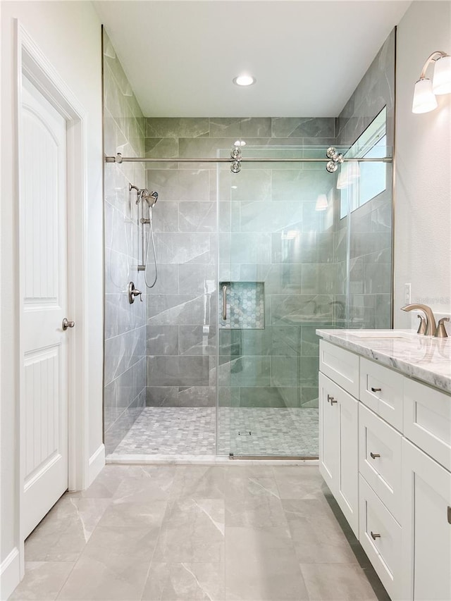 bathroom featuring tile patterned floors, a shower with door, and vanity