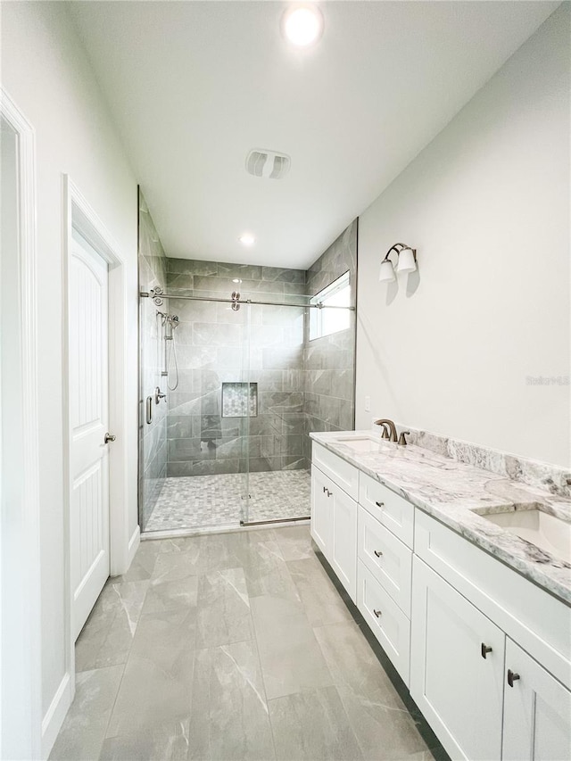 bathroom with a shower with door, vanity, and tile patterned floors