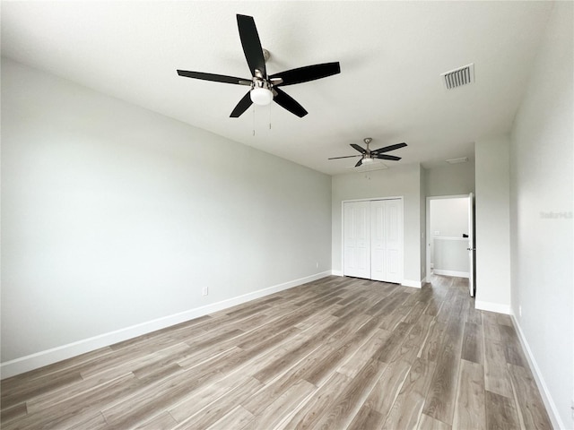 unfurnished bedroom featuring ceiling fan, a closet, and light hardwood / wood-style floors