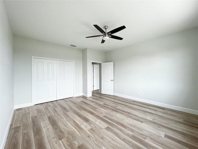 unfurnished bedroom featuring light wood-type flooring, ceiling fan, and a closet