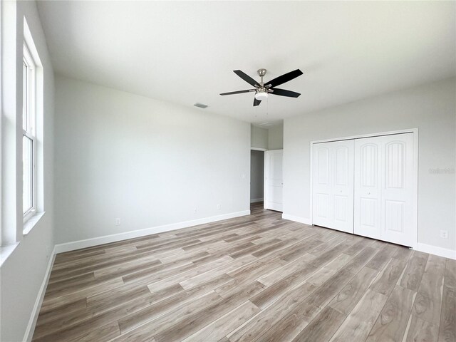 unfurnished bedroom featuring light wood-type flooring, ceiling fan, and a closet