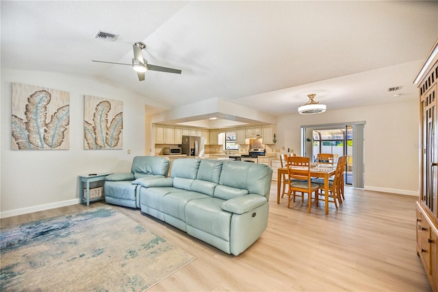 living room featuring ceiling fan, vaulted ceiling, and light hardwood / wood-style floors