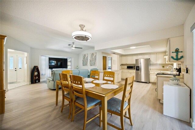 dining space featuring a textured ceiling, ceiling fan, sink, and light hardwood / wood-style floors