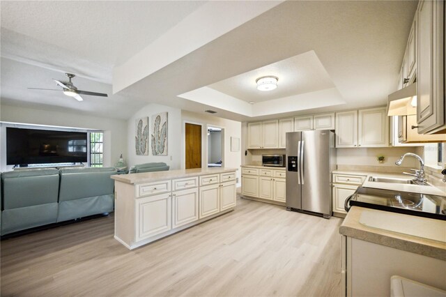 kitchen with sink, ceiling fan, a tray ceiling, appliances with stainless steel finishes, and light hardwood / wood-style floors