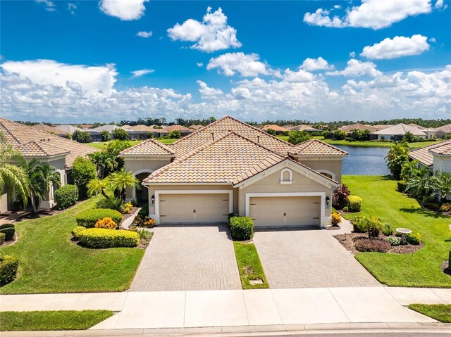 mediterranean / spanish home with a garage, a water view, and a front lawn