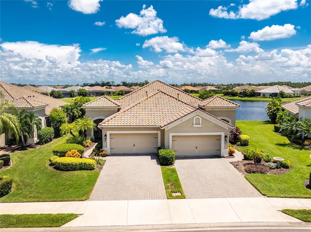 mediterranean / spanish-style home with a garage, a tiled roof, decorative driveway, stucco siding, and a front yard