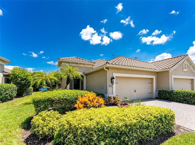 view of front of home with a garage, stucco siding, decorative driveway, and a tiled roof