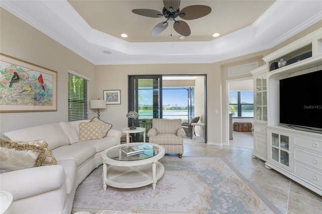 living room featuring a tray ceiling, ceiling fan, light tile patterned floors, and crown molding