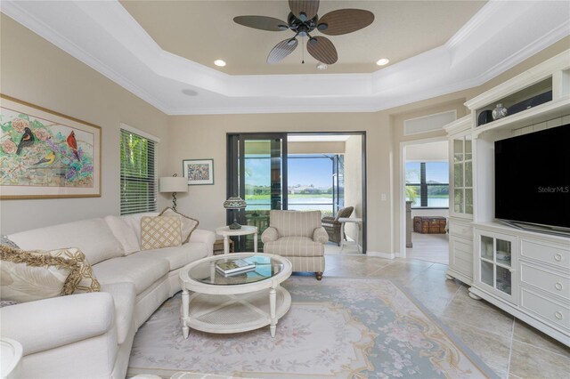 living room featuring light tile patterned floors, a tray ceiling, and ornamental molding