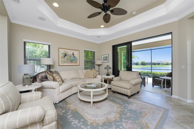 living room featuring a tray ceiling, light tile patterned flooring, crown molding, and baseboards