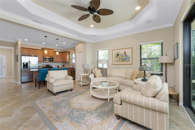 living room featuring a tray ceiling, ceiling fan, light tile patterned floors, and ornamental molding