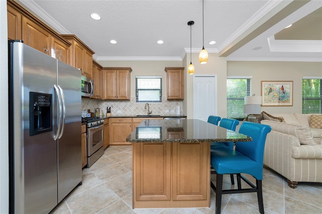 kitchen with stainless steel appliances, open floor plan, a sink, a kitchen island, and dark stone counters