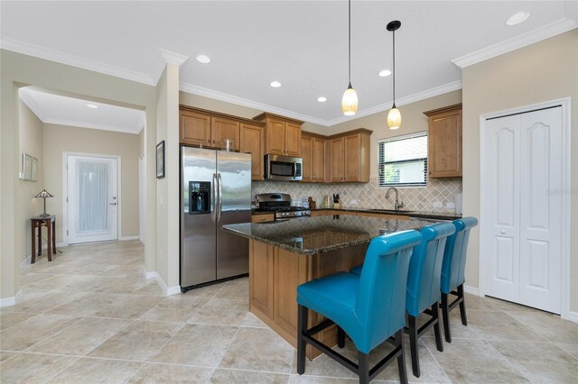 kitchen with dark stone countertops, a center island, stainless steel appliances, sink, and a breakfast bar