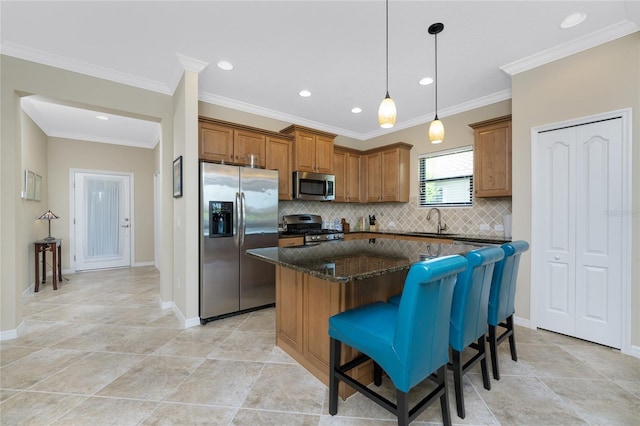 kitchen featuring a kitchen island, a sink, appliances with stainless steel finishes, brown cabinets, and dark stone countertops