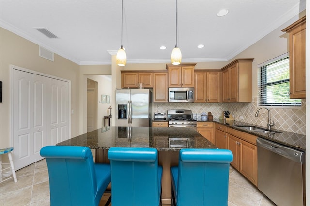 kitchen featuring dark stone countertops, a center island, appliances with stainless steel finishes, sink, and pendant lighting