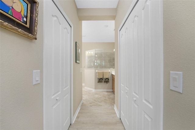 hallway featuring light wood-type flooring and baseboards