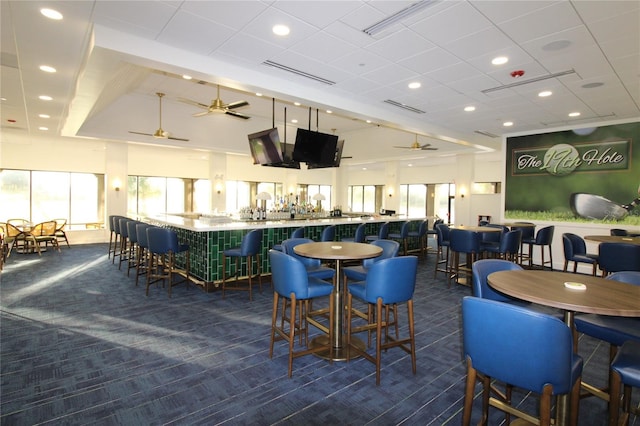 dining room with dark carpet, ceiling fan, and indoor bar