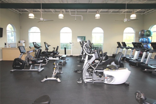 exercise room with ceiling fan and baseboards