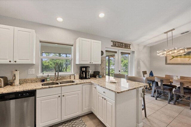 kitchen with stainless steel dishwasher, a healthy amount of sunlight, decorative light fixtures, and vaulted ceiling