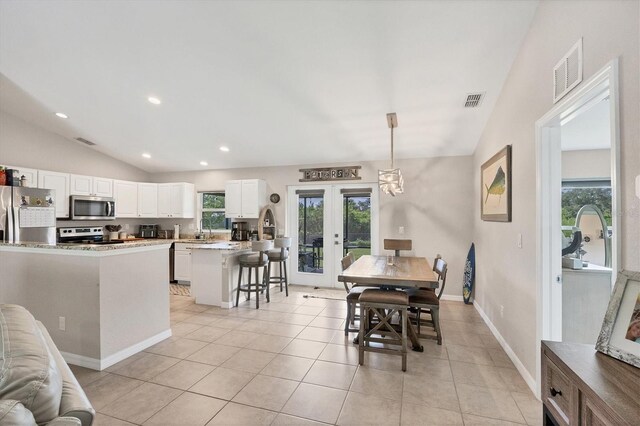 tiled dining space with lofted ceiling, sink, and french doors