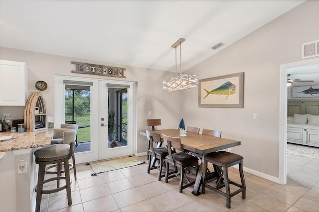 dining area with french doors, ceiling fan with notable chandelier, light tile patterned flooring, and vaulted ceiling