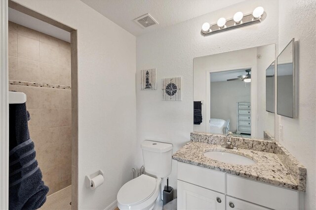 bathroom with vanity, toilet, ceiling fan, and a textured ceiling