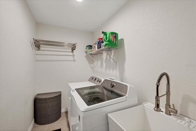 clothes washing area featuring washing machine and dryer, sink, and light tile patterned floors