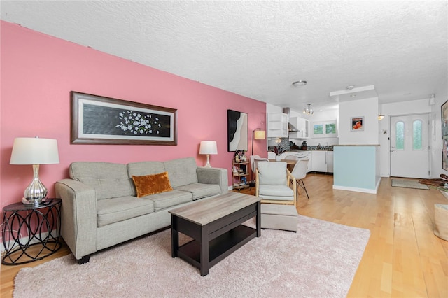 living room with a textured ceiling and light wood-type flooring