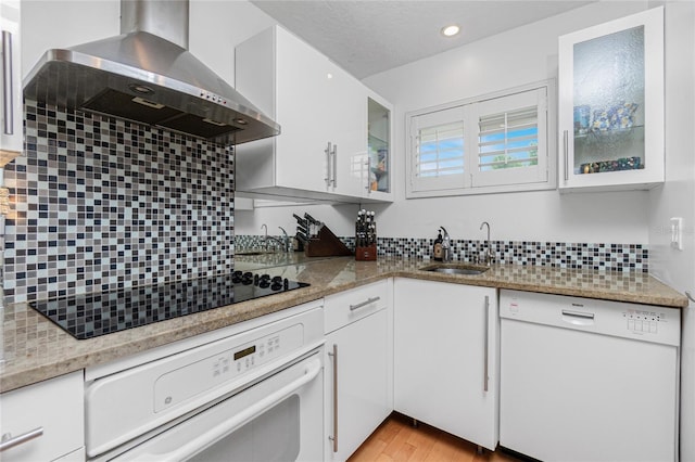 kitchen featuring white appliances, white cabinetry, wall chimney exhaust hood, and sink