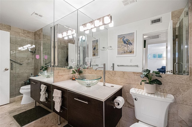 bathroom with walk in shower, vanity, tile walls, and toilet