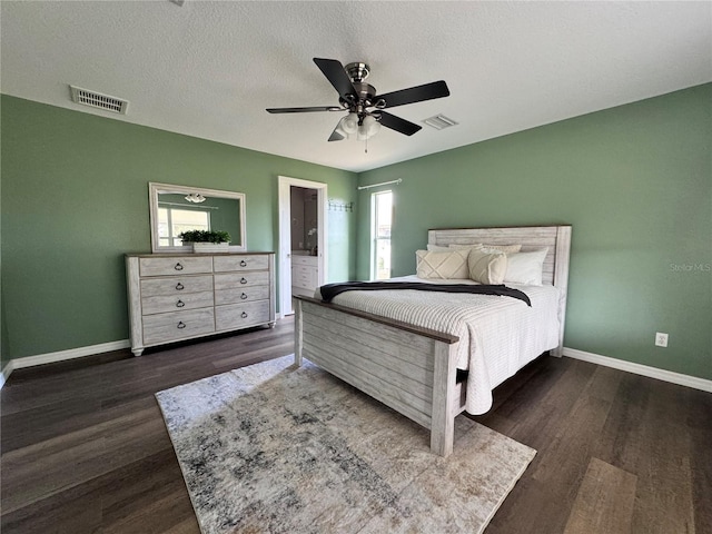 bedroom featuring ceiling fan, ensuite bathroom, dark hardwood / wood-style flooring, and a textured ceiling