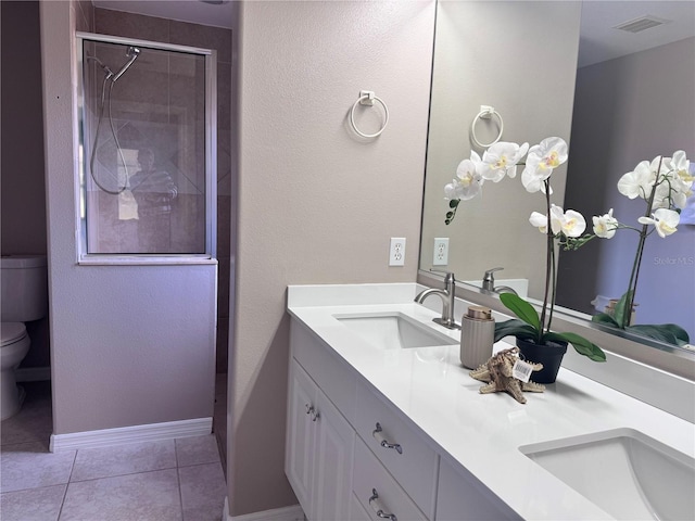 bathroom with tile patterned flooring, vanity, a tile shower, and toilet