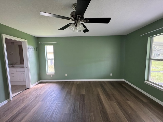 unfurnished bedroom with connected bathroom, sink, ceiling fan, dark wood-type flooring, and a textured ceiling