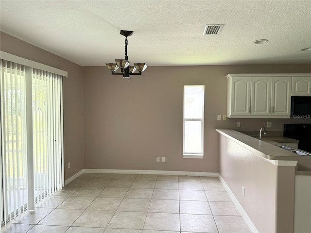 kitchen with a wealth of natural light, white cabinets, a chandelier, hanging light fixtures, and light tile patterned floors