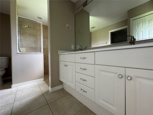 bathroom featuring vanity, tile patterned floors, toilet, and tiled shower