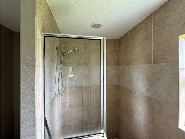 bathroom featuring a shower with door and a textured ceiling