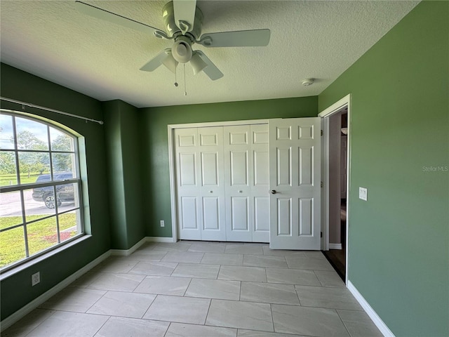 unfurnished bedroom featuring a textured ceiling, a closet, ceiling fan, and light tile patterned flooring