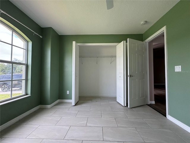 unfurnished bedroom with multiple windows, a textured ceiling, ceiling fan, and a closet