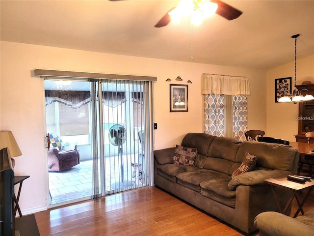 living room featuring ceiling fan with notable chandelier, hardwood / wood-style flooring, and vaulted ceiling