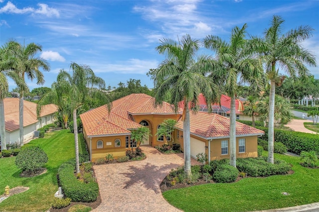 view of front of house featuring a front yard, stucco siding, a garage, a tile roof, and decorative driveway