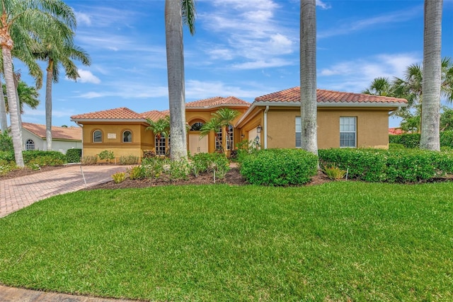 mediterranean / spanish house with stucco siding, decorative driveway, a front lawn, and a tile roof